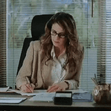 a woman is sitting at a desk with a pen in her hand .