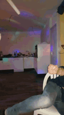 a person sitting on a chair in a kitchen with purple lights behind them