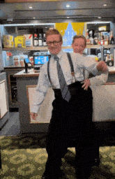 two men in suspenders are dancing in front of a bar