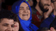 a woman wearing a blue hijab is smiling in a crowd
