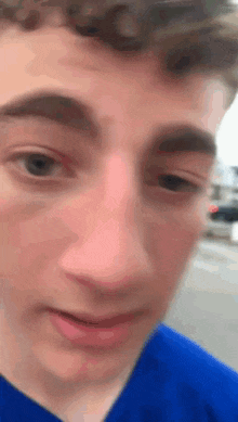a close up of a person 's face with a blue shirt on .