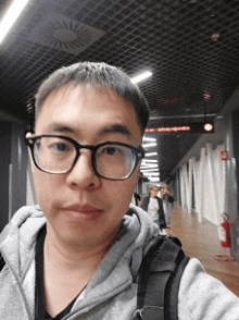 a man wearing glasses and a backpack is taking a selfie .