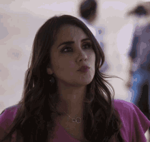 a woman wearing a pink shirt and a necklace with two rings on it