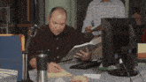 a man sits at a desk looking at papers and writing on a piece of paper
