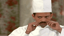 a man in a chef 's uniform has a fake mustache on his face