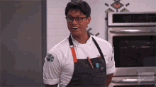 a man wearing a chef 's uniform and apron stands in front of an oven that says bravo on it