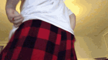 a man wearing a white shirt and red and black plaid pants