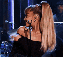a woman singing into a microphone with a ponytail on