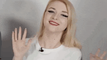 a woman wearing a white shirt and a microphone is smiling .