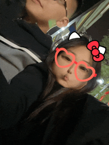 a girl wearing heart shaped glasses with a hello kitty bow on them