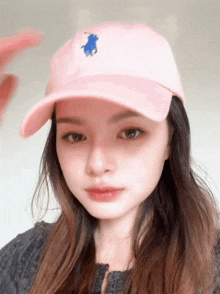 a young woman wearing a pink hat with a blue horse on it