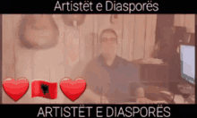 a man is sitting at a desk with hearts and the words artistet e diasporas in the corner