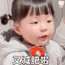 a little girl with chinese writing on her face is holding a candy