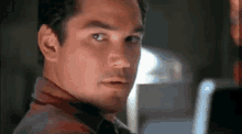 a close up of a man 's face looking at the camera in a room .