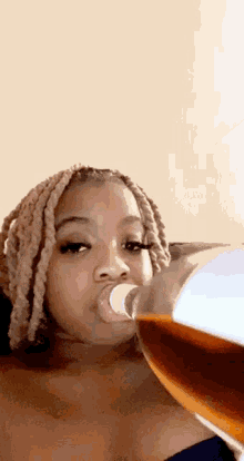 a woman is drinking soda from a bottle with her tongue out .