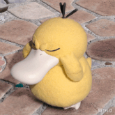 a stuffed yellow duck with a white beak is sitting on a brick sidewalk with netflix written on the bottom