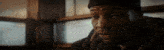 a man in a beanie is sitting in front of a window and looking at something .