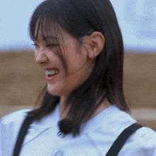 a woman with her eyes closed is wearing a white shirt and black suspenders