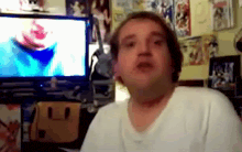a man in a white shirt is sitting in front of a tv