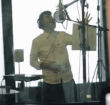 a man singing into a microphone in front of a window