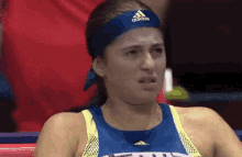 a woman wearing an adidas headband is making a face