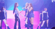 a group of women are dancing on a stage with a sign behind them that says ' kpop '