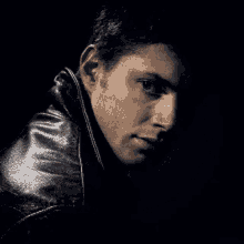 a man wearing a black leather jacket is looking down