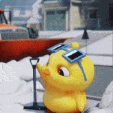 a yellow rubber duck wearing blue sunglasses is standing in the snow