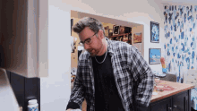 a man in a plaid shirt stands in front of a counter