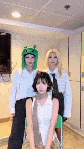 a woman wearing a green hat with a frog on it poses with two other women