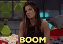 a woman is sitting on a bed with the word boom written on her chest