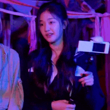 a girl is holding a camera in her hand and looking at the camera .