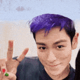 a man with purple hair is making a peace sign with his fingers