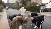 a group of people standing on the side of a road with one wearing a pink beanie