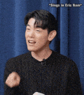a man wearing a black sweater and a microphone pointing at something