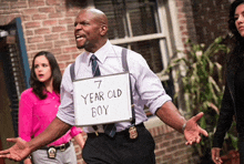 a man holding a sign that says " 7 year old boy "
