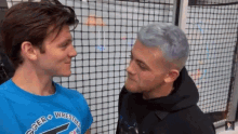 two men are looking at each other and one has a shirt that says soccer wrestlers on it