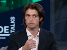 a man in a suit and white shirt is sitting in front of a sign that says side talks