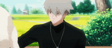 a man with gray hair is wearing a black turtleneck and a silver necklace .