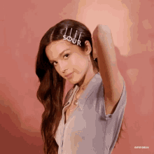 a woman wearing a purple shirt and a hair clip that says sour on it .