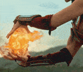 a person wearing red gloves holds a ball of fire in their hands