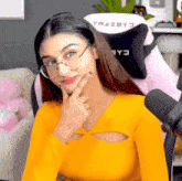 a woman wearing glasses and a yellow shirt is sitting in a pink chair that says tracby