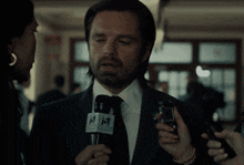 a man in a suit and tie is being interviewed by a woman while holding a microphone .
