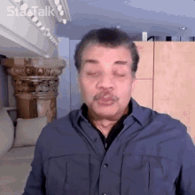 a man with his eyes closed is wearing a blue shirt and a mustache .