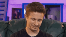 a man is sitting on a couch with his eyes closed and making a funny face .