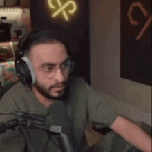 a man is wearing headphones and glasses while sitting in front of a microphone .