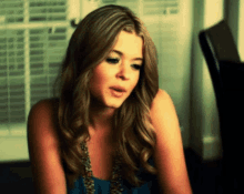 a woman in a blue tank top is looking at something