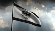 a black and white flag with an eagle on it is flying in the wind