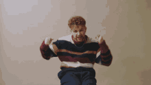 a man wearing a striped sweater is flexing his muscles
