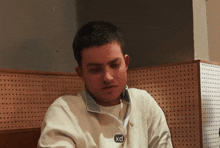a man wearing a white jacket with a xd button on the front